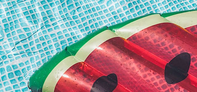 watermelon pool float in a blue pool on a summer day.
