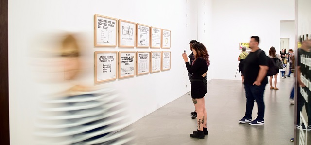a person taking photos of an art display on the wall in a gallery