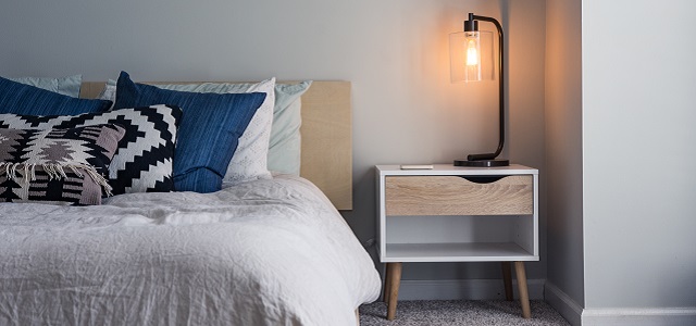a brightly lit lamp on a bed side table