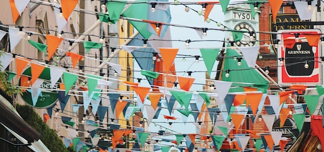 irish colored flags hanging from the buildings above a street