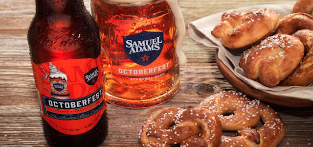 Two bottles of Sam Adams Octoberfest and hot salted pretzels on a wooden table.