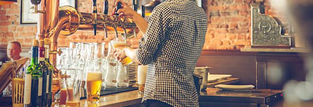 woman standing behind the bar pouring a beer for a customer.